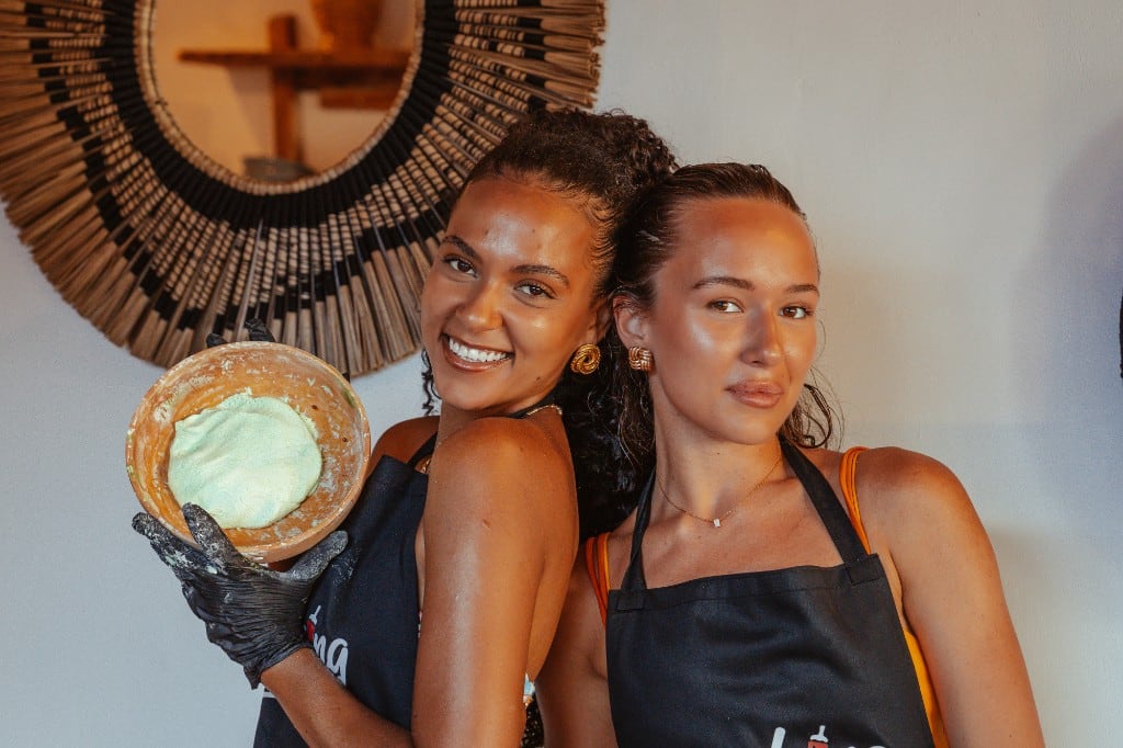 Two guests in Cooking on Meno aprons making klepon dough by hand during a cooking class on Gili Meno